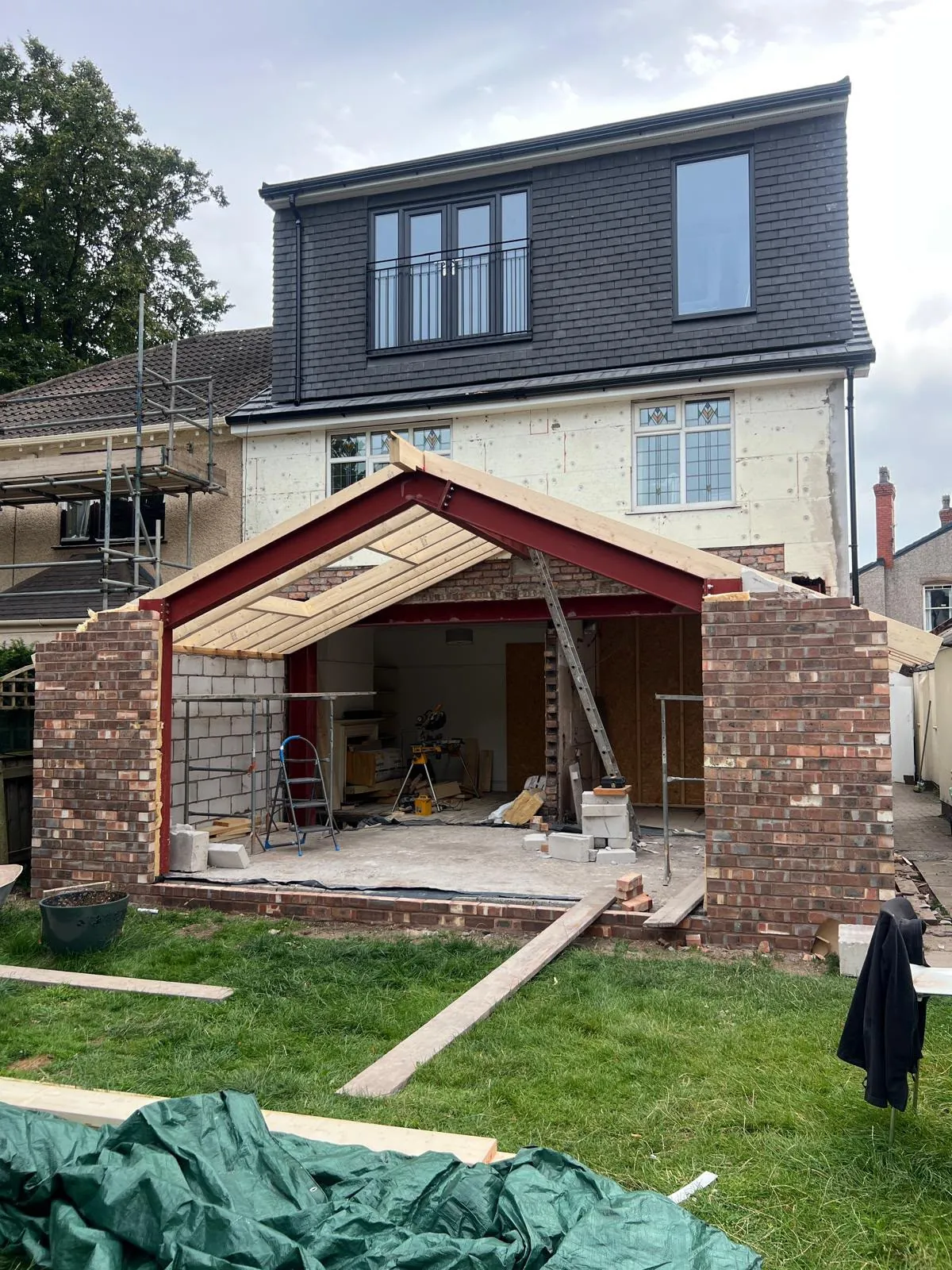 House extension under construction with steel frame and roof timbers