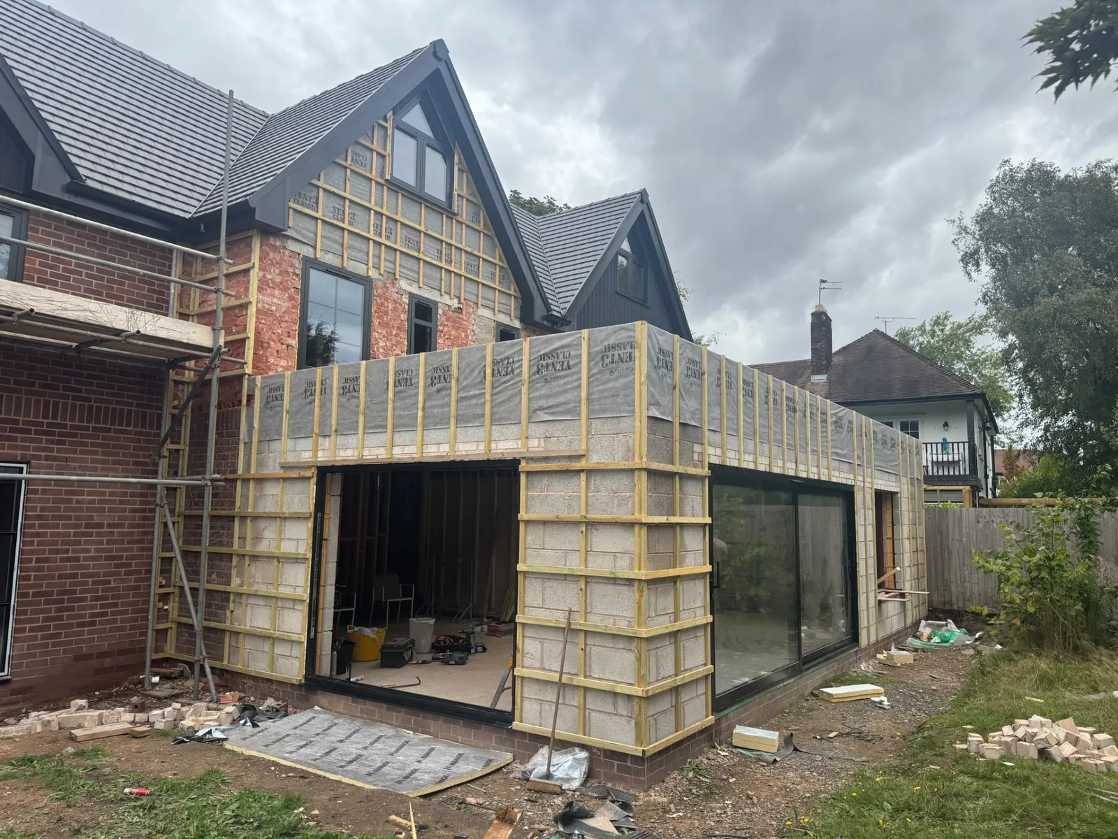Large extension in progress with timber roof framing, insulation and sliding doors