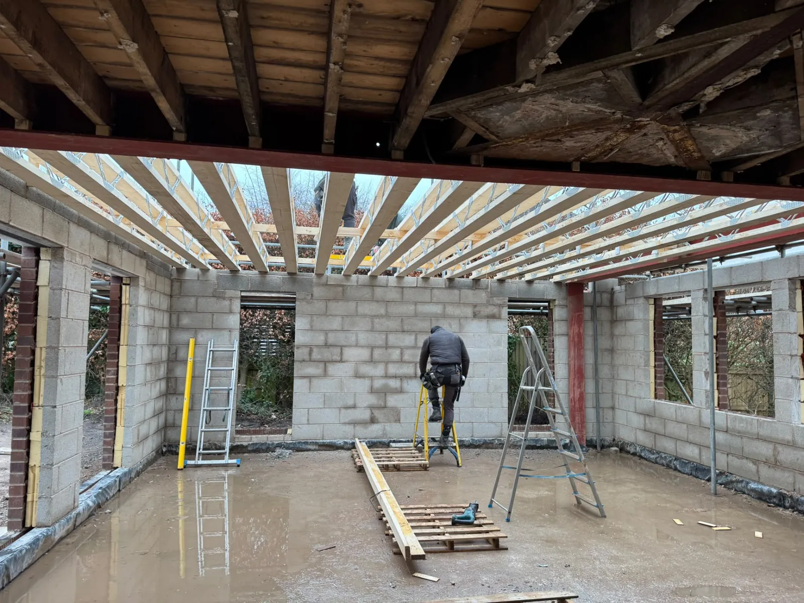 Builder working inside an extension with block walls and roof joists