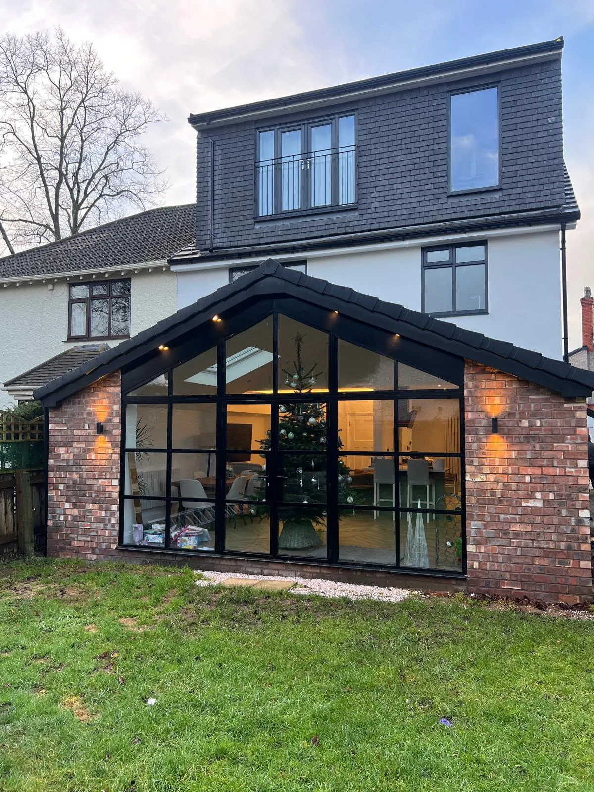 Finished upper-storey extension with dark cladding above a glazed brick garden room