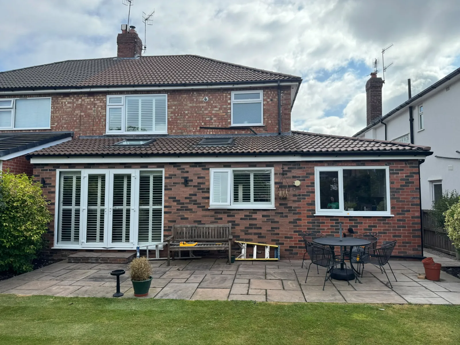 Brick rear house extension with patio doors and garden patio, alternative view
