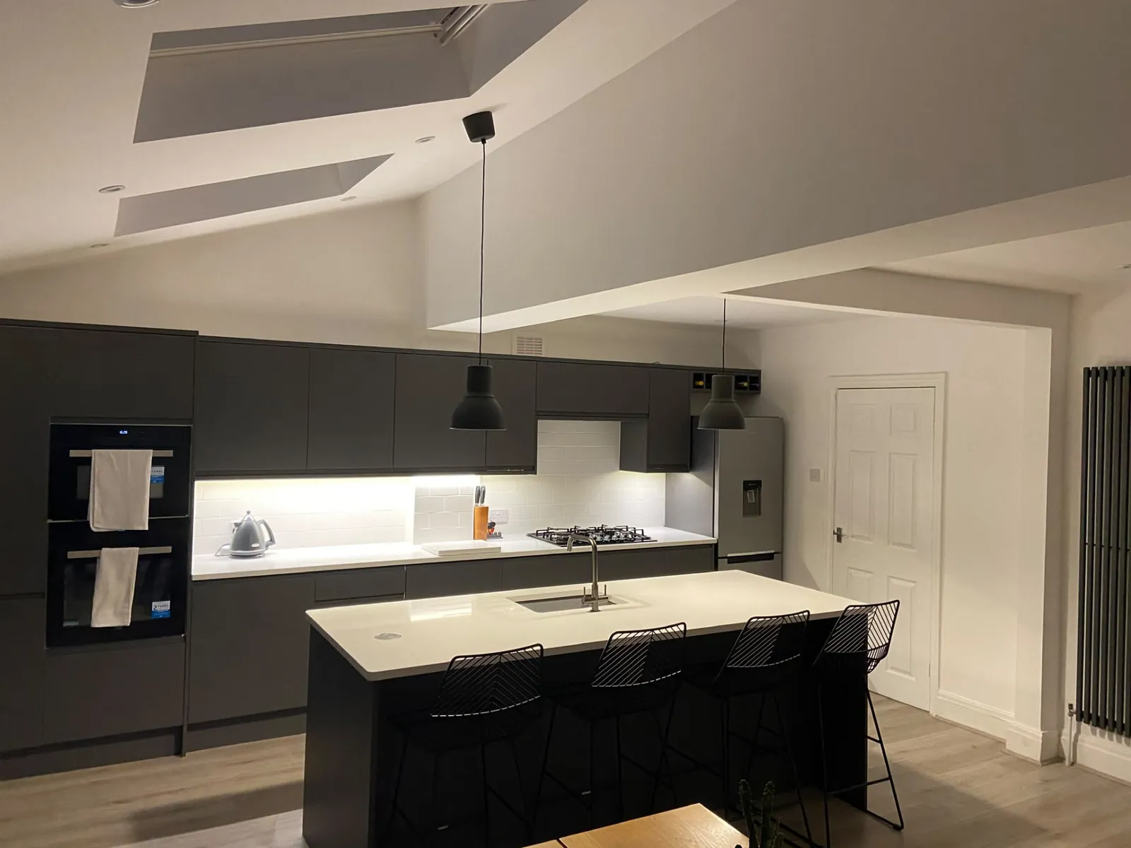 Finished handleless grey kitchen with island, pendant lights and vaulted ceiling