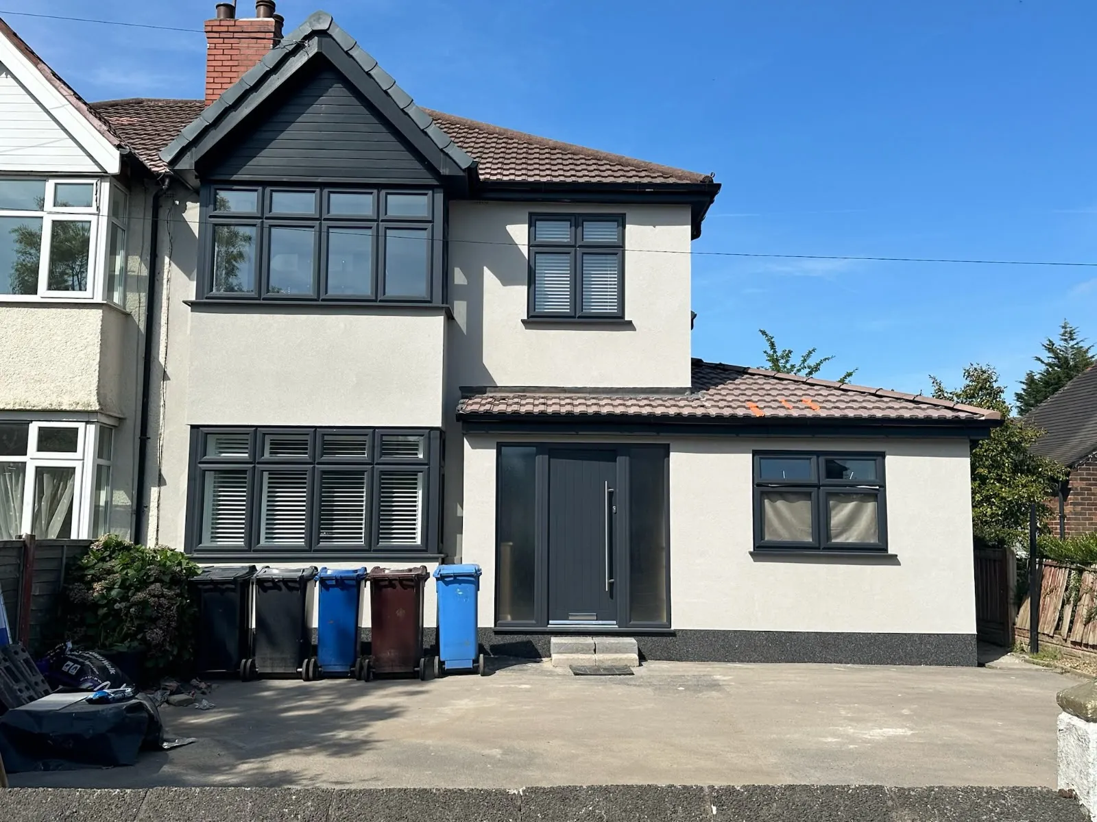 Completed two-storey side extension with white render, dark windows and driveway